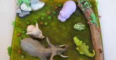 there are many toy animals in the pond on this table top, including an elephant and two other animal figurines