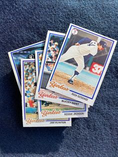 four baseball cards are stacked on top of each other in front of a blue carpet