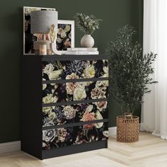 a black and white floral print dresser next to a potted plant in a room with green walls