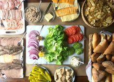 a table topped with lots of different types of food next to breads and vegetables