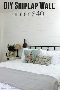 a bed with white sheets and pillows under the wall that says diy shiplap wall under $ 40