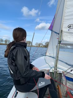 a woman sitting on the bow of a sailboat