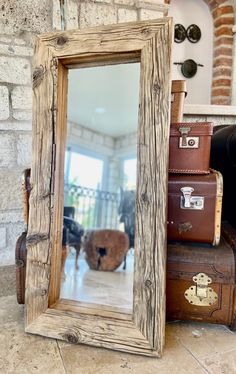 a mirror sitting on top of a table next to suitcases and a brick wall