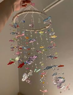 a hand holding a wind chime with many butterflies hanging from it's side