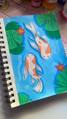 a notebook with an image of two koi fish in water and lily pads on the cover