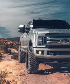 a silver truck driving down a dirt road