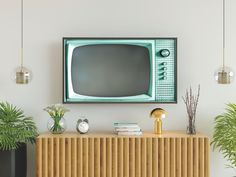 a pink television sitting on top of a wooden cabinet next to two potted plants