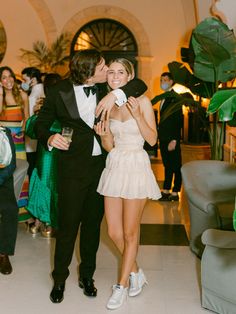 a man in a tuxedo kisses a woman's cheek as they pose for the camera