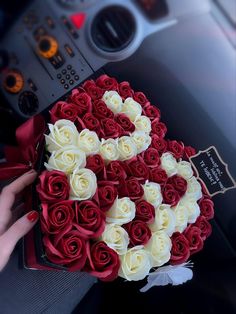 a bouquet of red and white roses in the shape of a letter g on a car dashboard