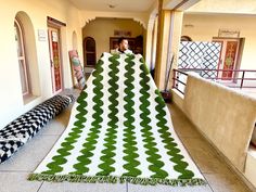 a large green and white blanket sitting on top of a floor next to a bench