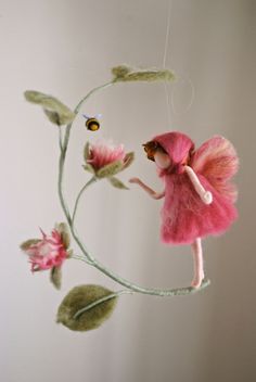 a pink fairy doll hanging from a string with flowers on it's head and wings