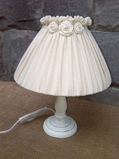 a lamp that is sitting on top of a burlap table cloth with white flowers