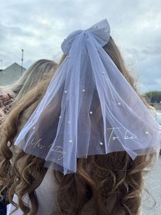 a woman wearing a veil with pearls on it's head is seen from behind