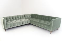 a green velvet sectional sofa with wooden legs