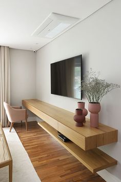 a flat screen tv sitting on top of a wooden shelf in a living room next to a window