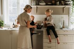 a mother and her child are washing dishes in the kitchen sink while they look at each other