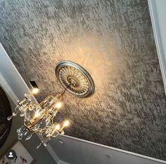 a chandelier hanging from the side of a wall in a room with grey walls