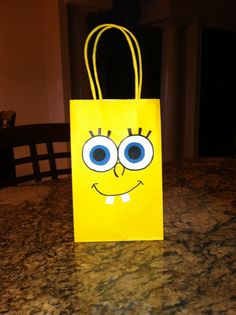 a yellow bag with blue eyes on it sitting on a counter top in front of a dining room table