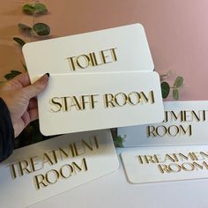 three signs that say hotel, staff room, treatment room and toilet in gold lettering