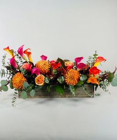 an arrangement of flowers in a wooden box on a white background with greenery and leaves