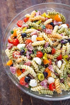 a pasta salad in a glass bowl on top of a wooden table with text overlay