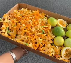 a box filled with lots of different types of pasta next to limes and lemons