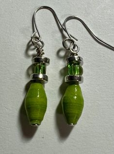 two green glass beads are hanging from silver earwires