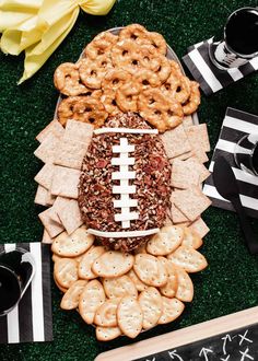 a football shaped platter with crackers, pretzels and cookies on it