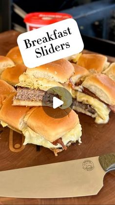 a wooden cutting board topped with lots of sliders next to a knife and some ketchup