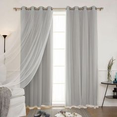 a living room with white curtains and grey shoes on the floor in front of it