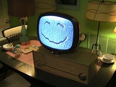 an old television sitting on top of a table with a smiley face drawn on it