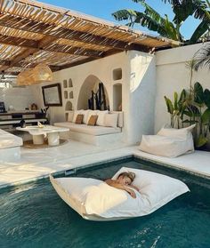 a woman laying on a bean bag in the middle of a pool with lounge chairs