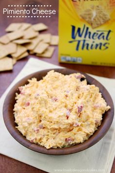 a wooden bowl filled with cheese next to crackers