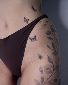 a woman's stomach with butterflies and leaves on her side, as if it were tattoos