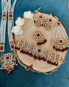 an assortment of necklaces and bracelets on a tree slice with flowers in the background