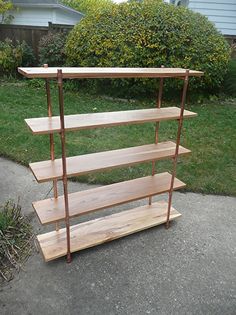 three wooden shelves sitting on the side of a road in front of some grass and bushes