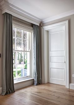 an empty room with a large window and wooden flooring in front of the door