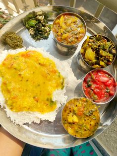 a silver plate topped with rice and different types of food on top of each other