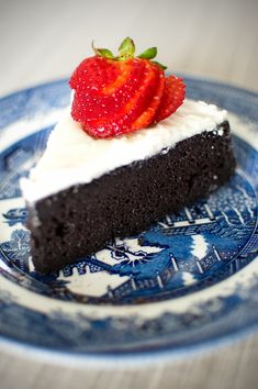 a piece of chocolate cake with whipped cream and strawberries on top is sitting on a blue plate