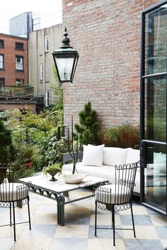 an outdoor living area with white furniture and brick walls