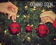 two people hanging ornaments from a christmas tree with the words daddy and mommy on them