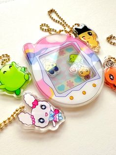 four keychains with cartoon characters on them sitting on a white surface, one has a chain around it and the other is holding a cell phone