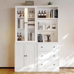 a white bookcase filled with lots of books next to a wall mounted shelf full of bottles