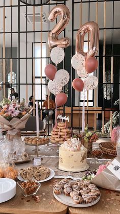 a table topped with lots of desserts and balloons in the shape of number two