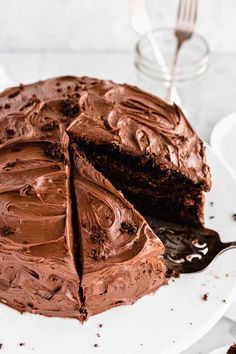 a chocolate cake on a white plate with a slice missing