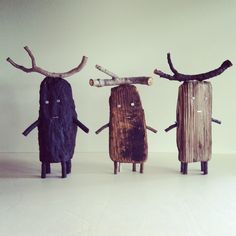 three wooden sculptures made to look like people with antlers on their heads and legs