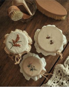 three embroidered coasters sitting on top of a wooden table