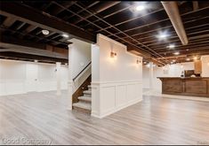 an empty room with white walls and wood flooring is pictured in this image, there are stairs leading up to the second floor