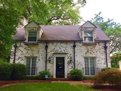 a white brick house with green grass and trees