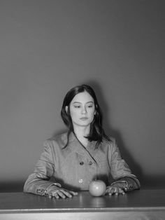 a woman sitting at a table with an apple in front of her